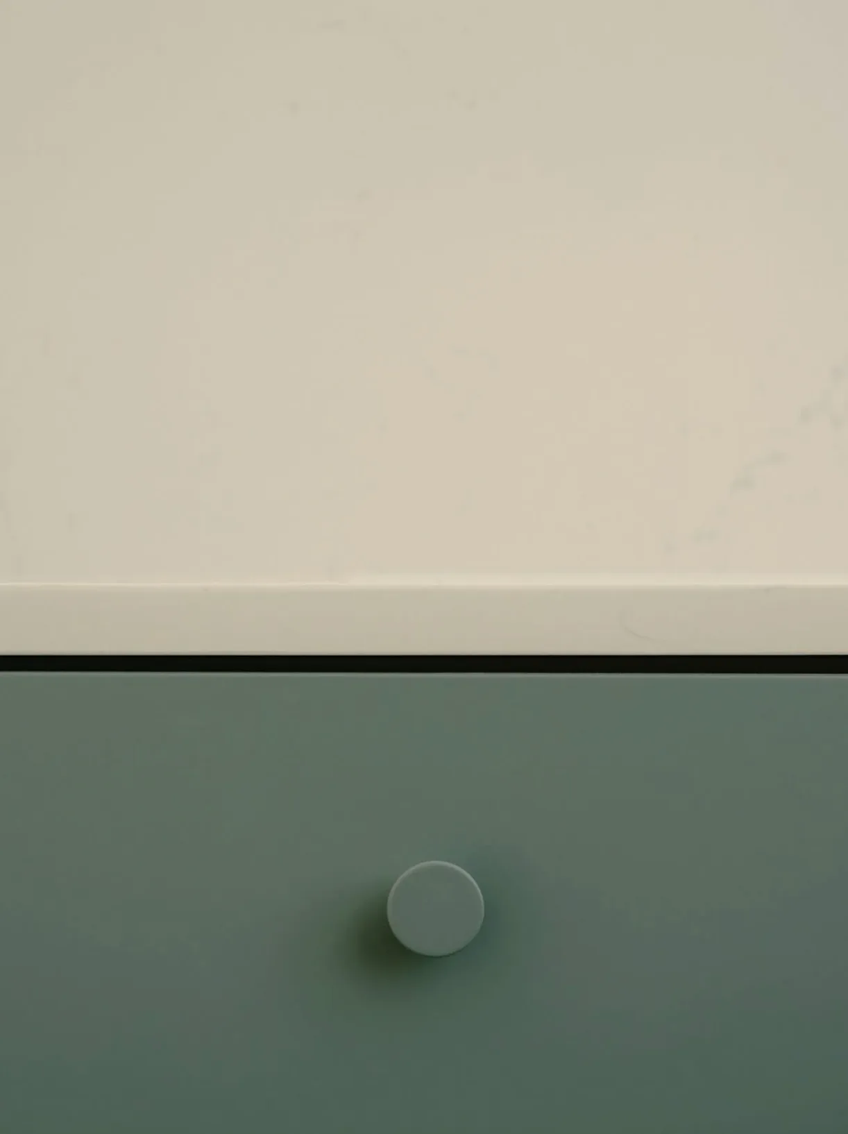 Detalle de un frente de cocina azul verdoso con tirador redondo